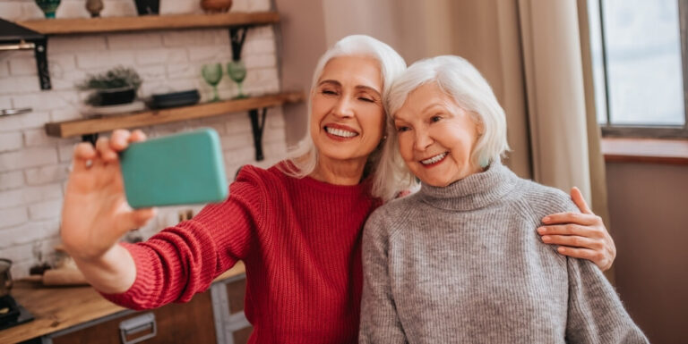 Two Elderly Women Taking a Selfie Together Inside a Kitchen at an Assisted Living Facility